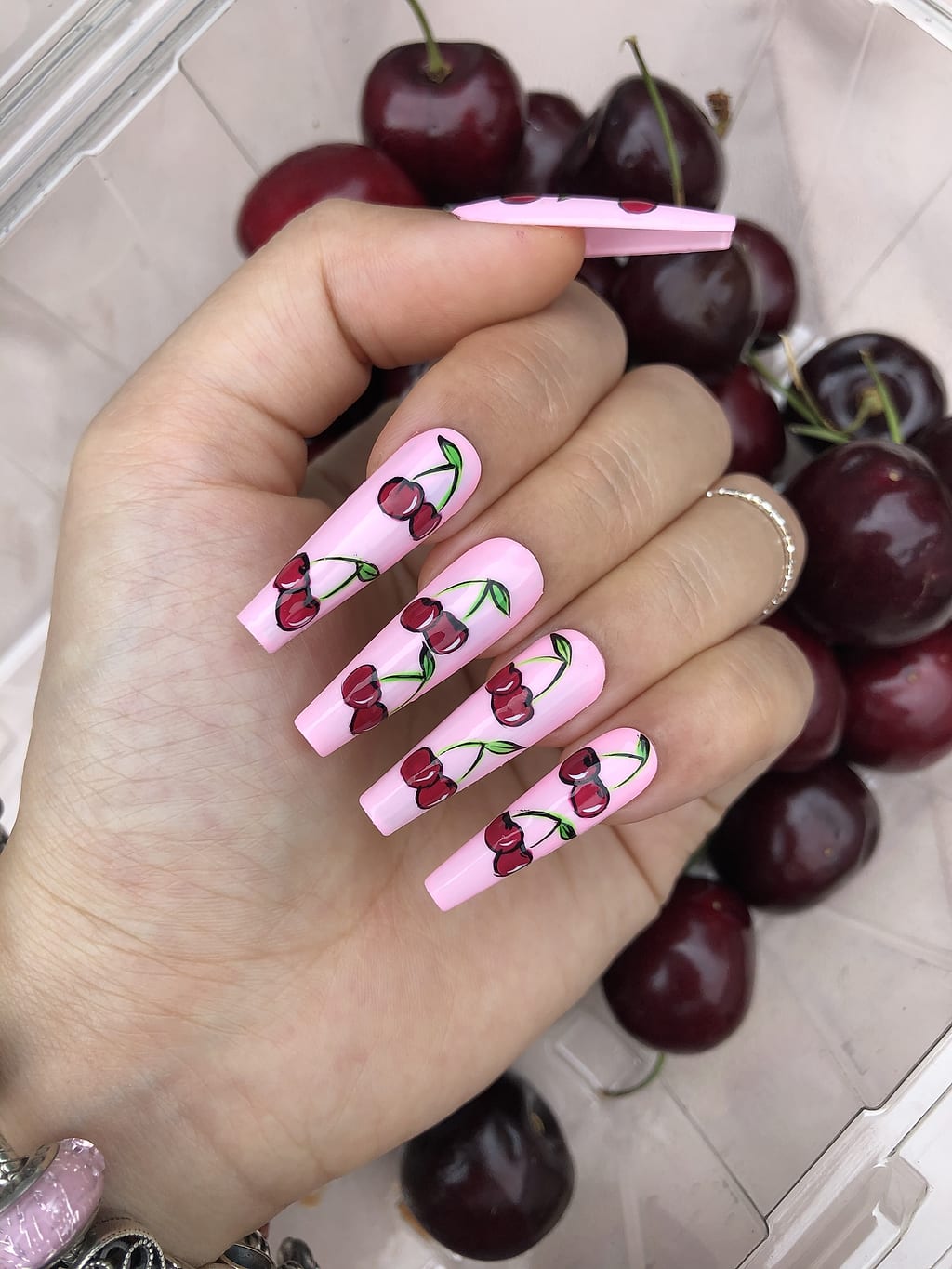 Pink coffin nails with a playful red cherry design at Palace Nail Spa in Midtown Tallahassee