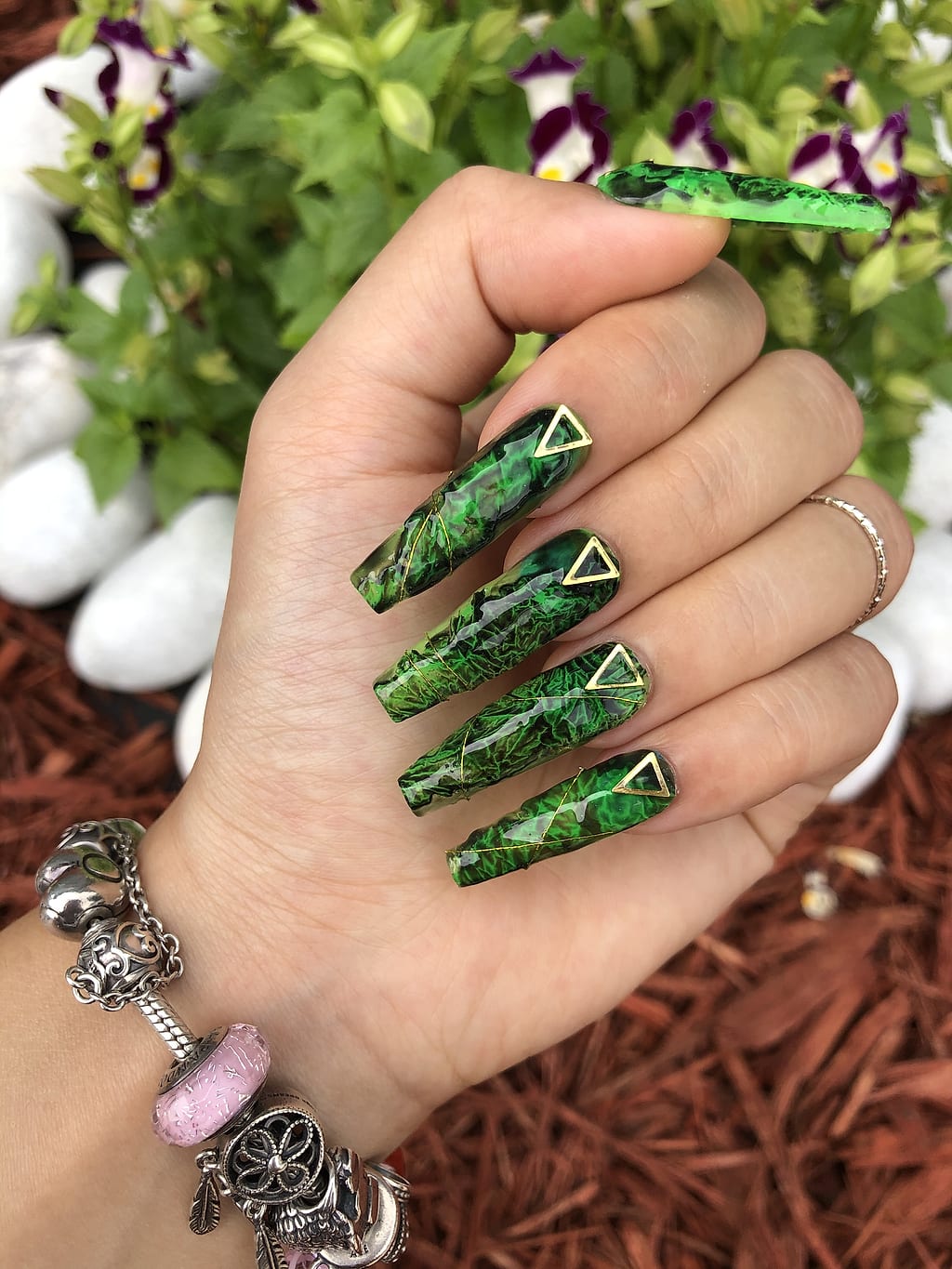 Long green glitter coffin nails with small triangle charms at Palace Nail Spa in Midtown Tallahassee