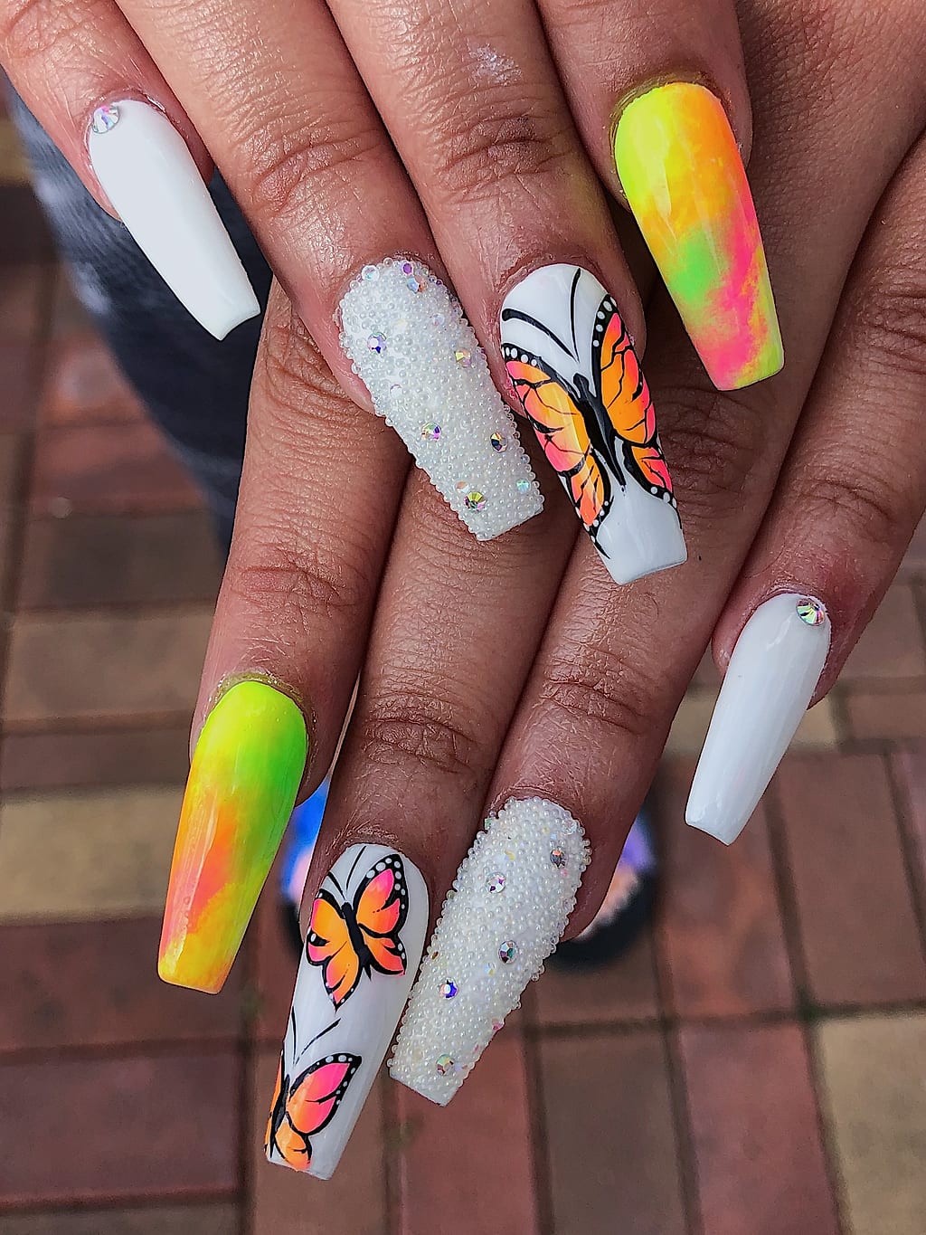 Coffin nails mixing white glitter, tie dye marble, and a butterfly accent at Palace Nail Spa