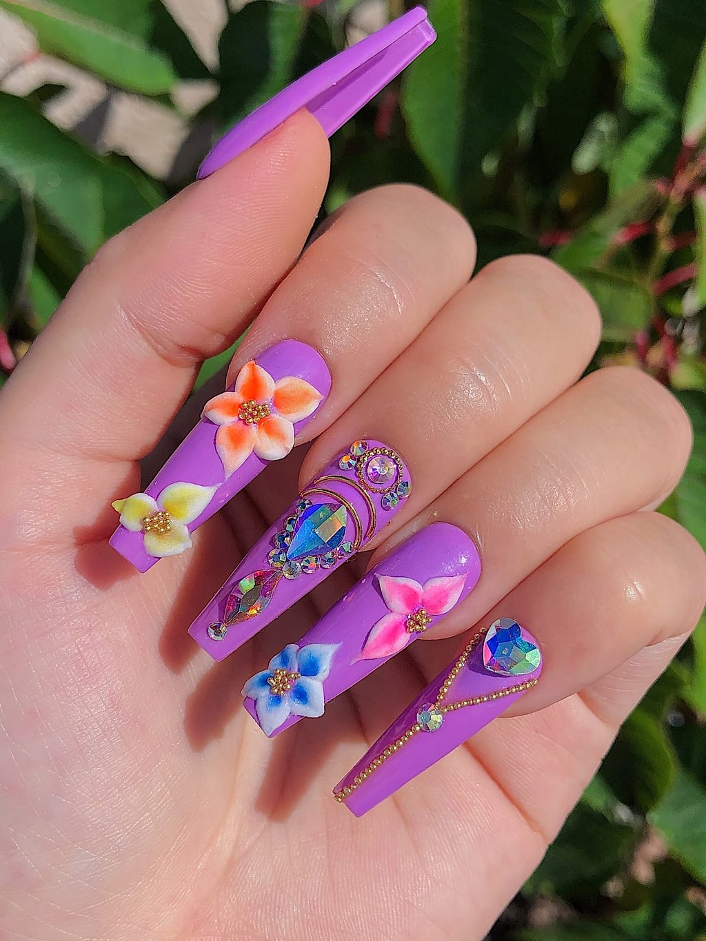 Purple coffin nails show hand-painted orange and pink florals at Palace Nail Spa in Midtown Tallahassee