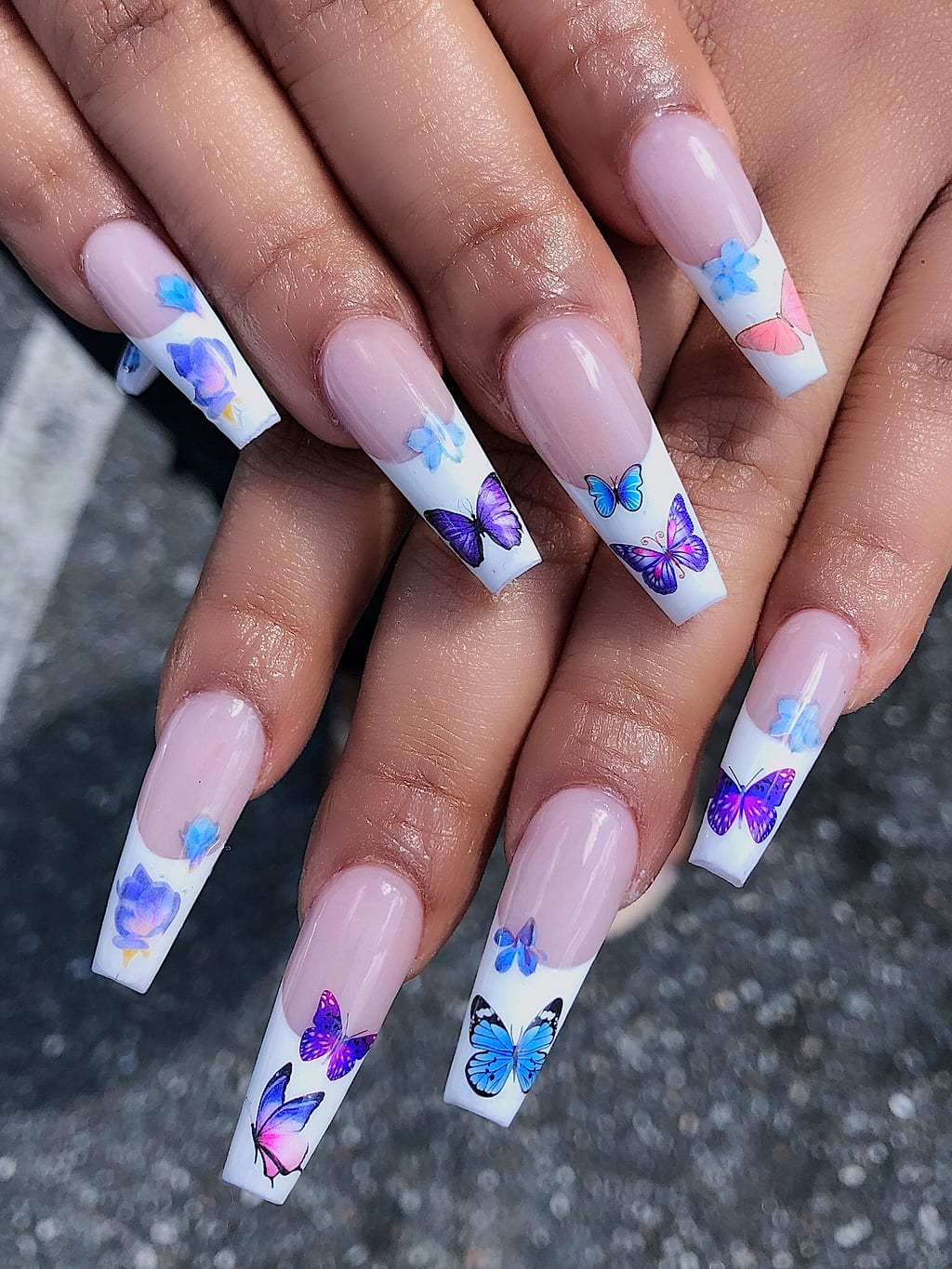 Coffin nails feature white French tips and purple butterflies at Palace Nail Spa in Midtown Tallahassee