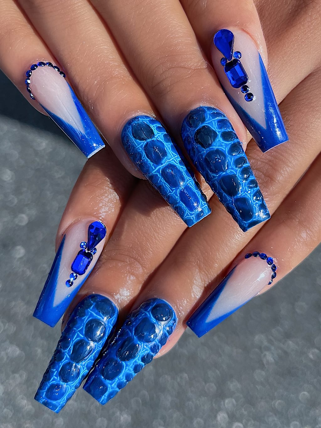 Blue and white coffin nails show a lace pattern with rhinestone accents at Palace Nail Spa
