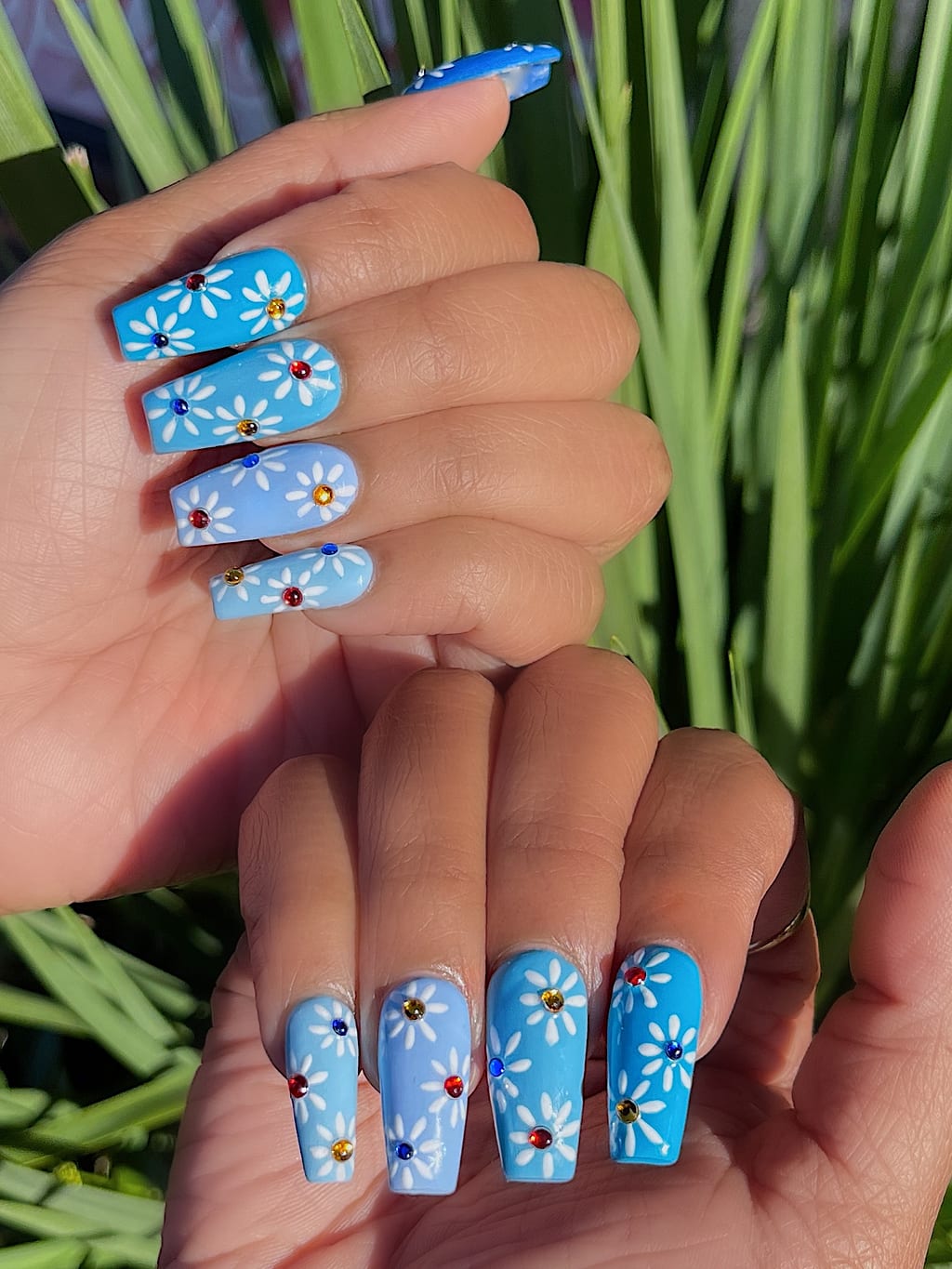 Light blue coffin nails feature painted white daisy flowers at Palace Nail Spa in Midtown Tallahassee