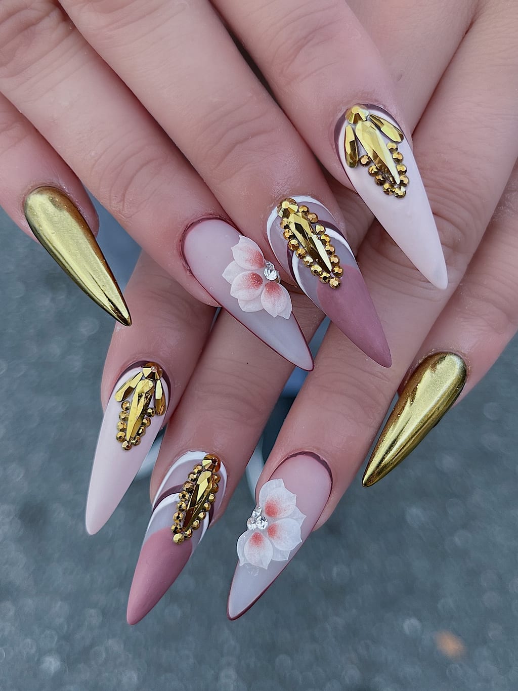 Nude and gold chrome stiletto nails feature delicate painted floral art at Palace Nail Spa