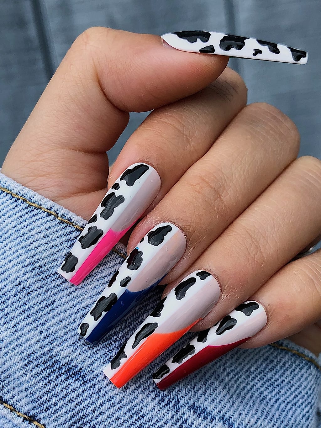 Black and white cow print coffin nails accented with neon orange tips at Palace Nail Spa