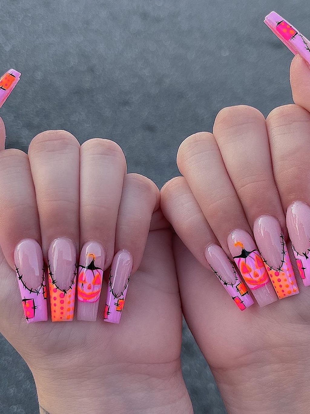 Neon orange and pink coffin nails feature Halloween pumpkin art at Palace Nail Spa in Tallahassee