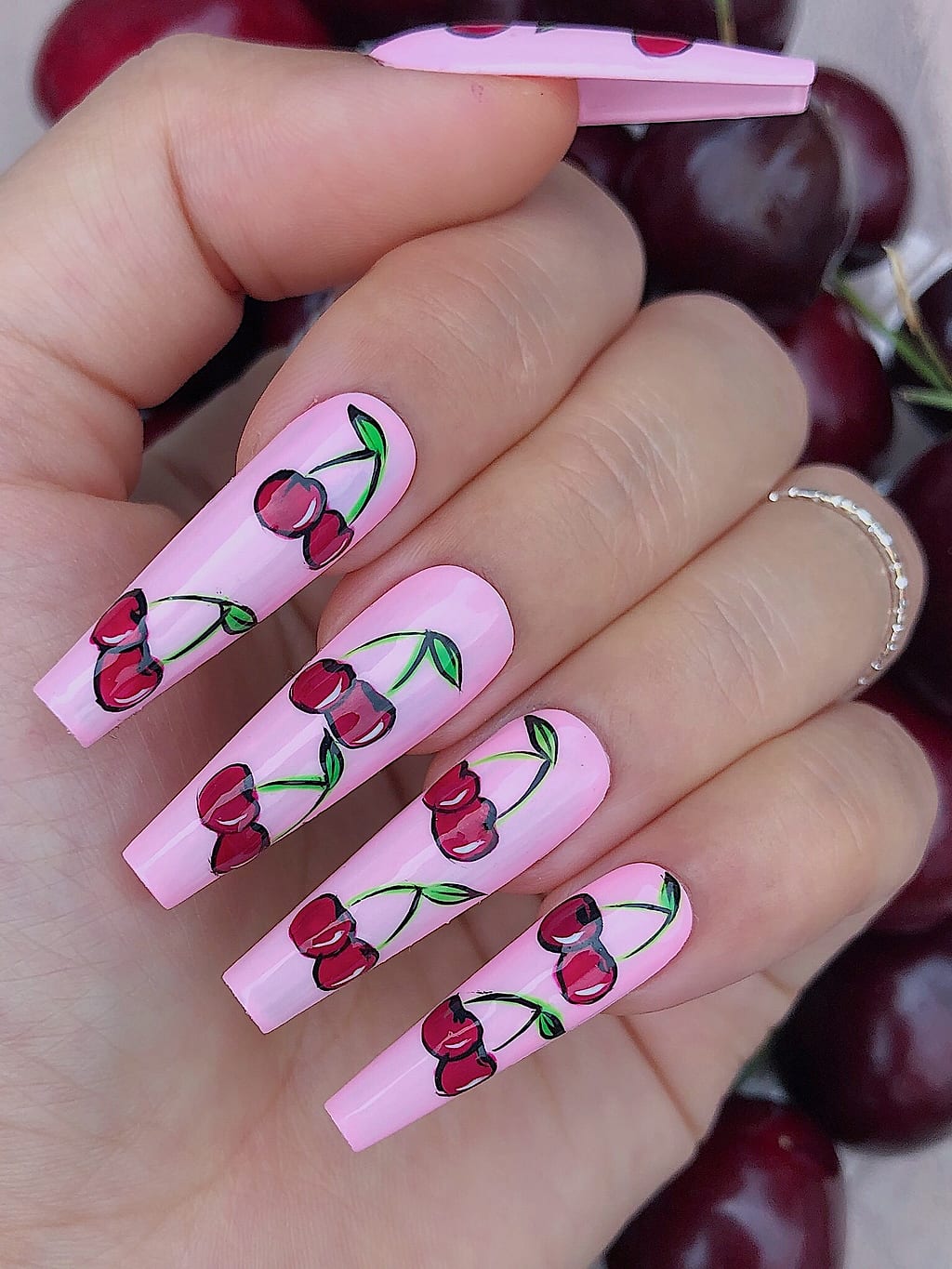 Pink coffin nails feature a bright red cherry design at Palace Nail Spa in Midtown Tallahassee