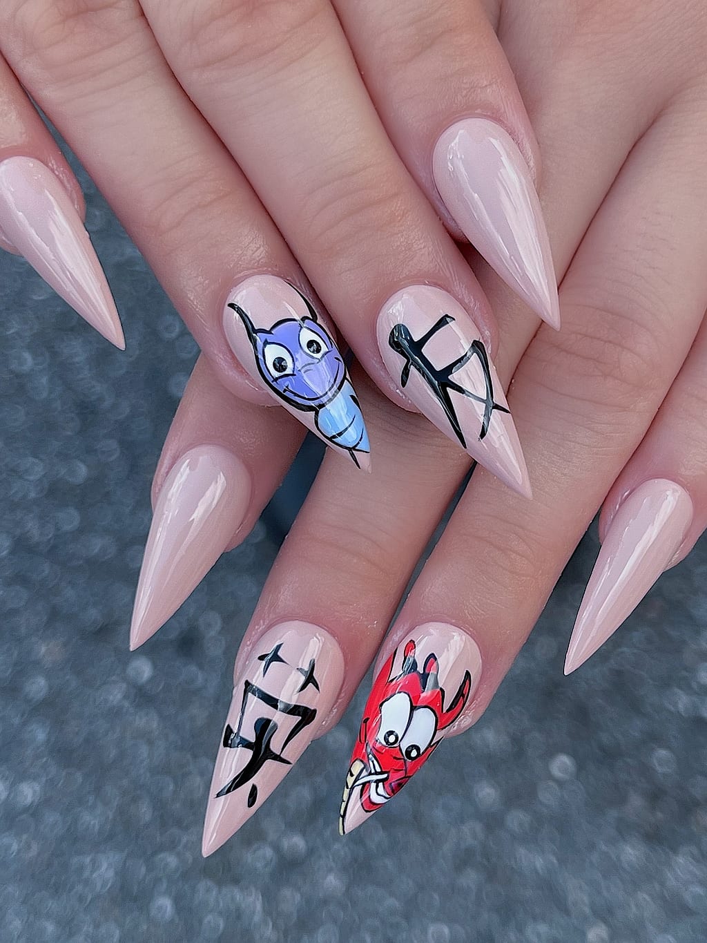 Nude almond nails feature quirky black line character art at Palace Nail Spa in Midtown Tallahassee