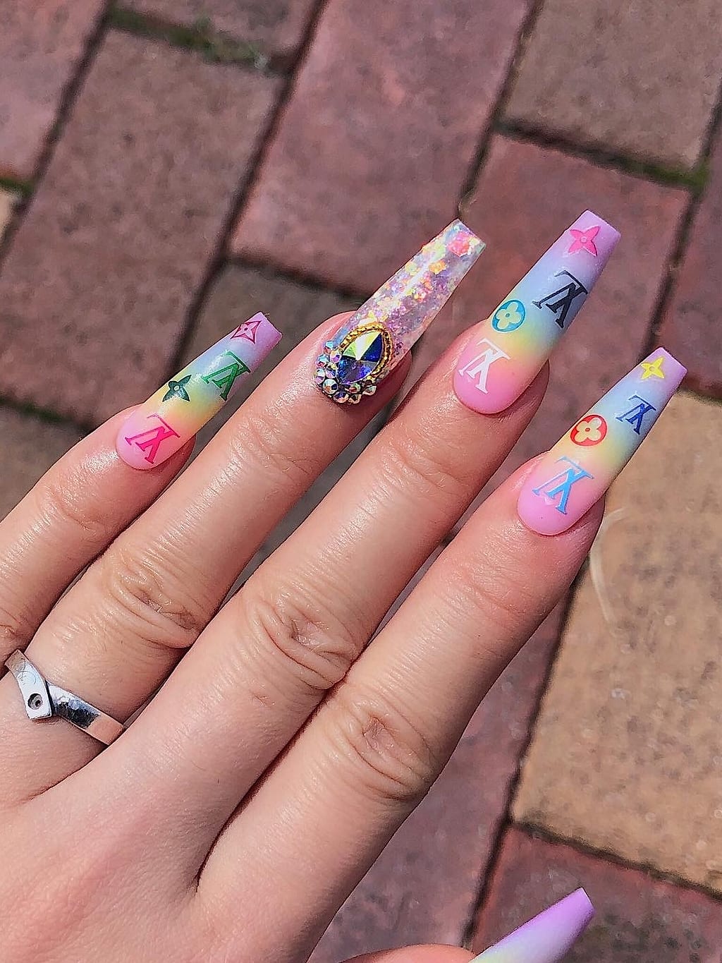 Nude coffin nails feature tiny colorful cartoon character art and gems at Palace Nail Spa