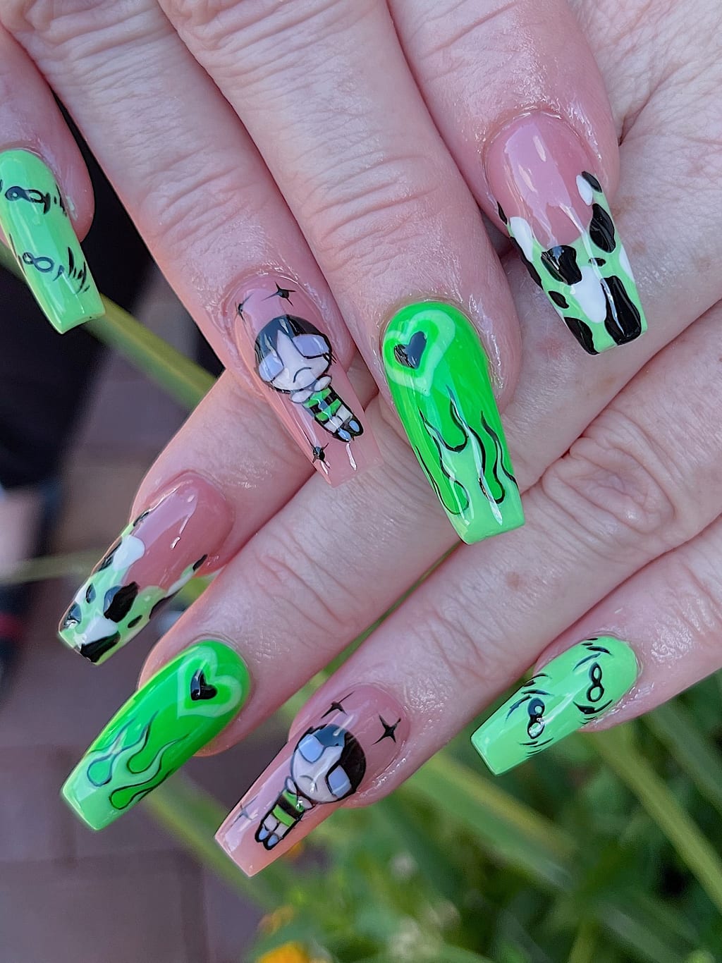 Bright green coffin nails with black cat and skull graphics at Palace Nail Spa in Tallahassee