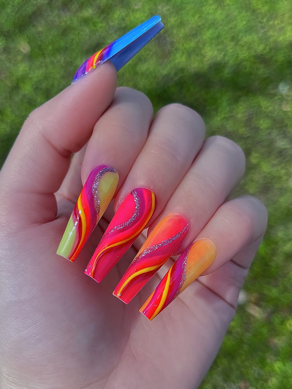 Coffin nails painted with fiery orange, red and yellow flame swirls at Palace Nail Spa