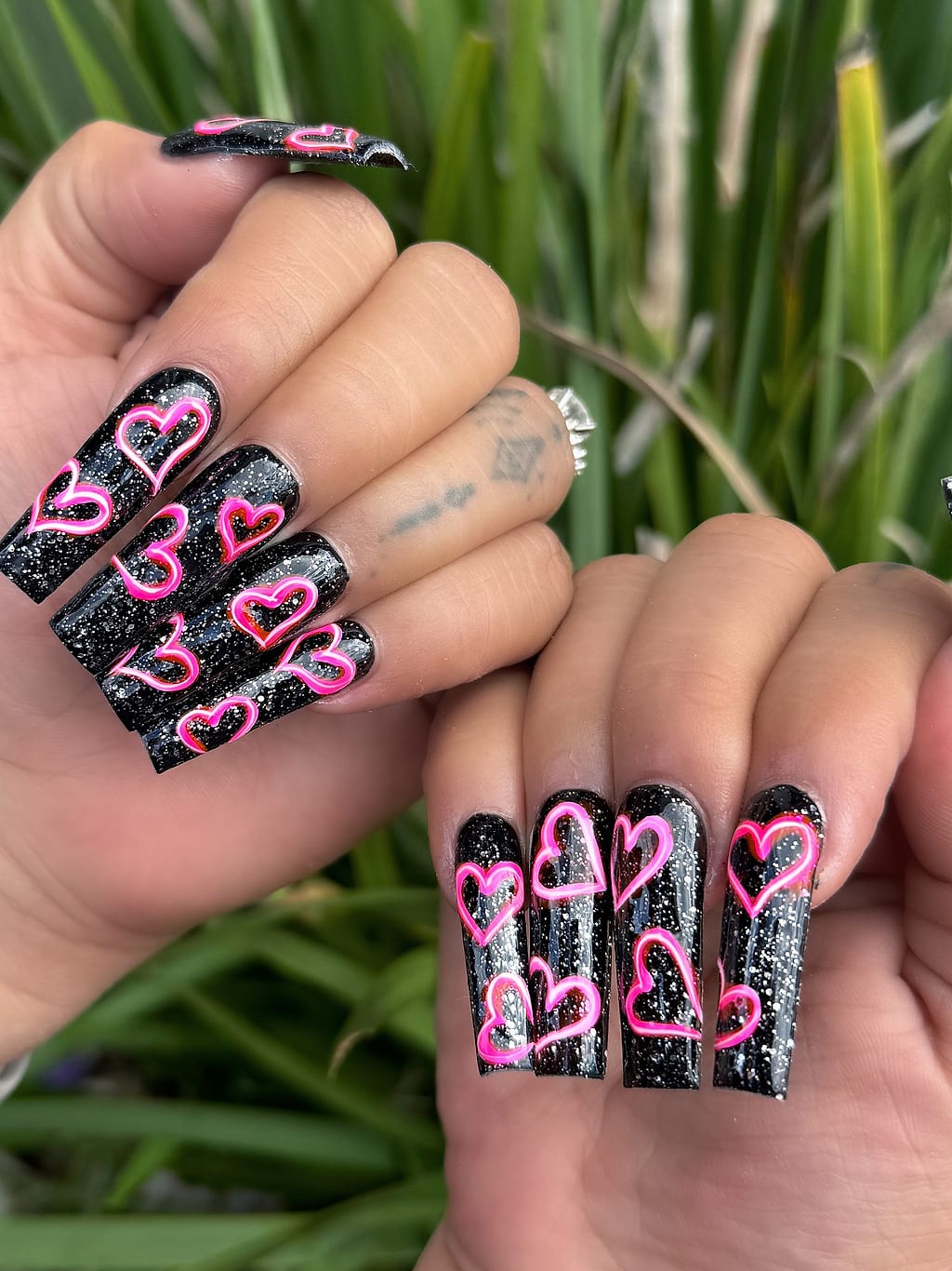 Black coffin nails with glittery pink heart outline art at Palace Nail Spa