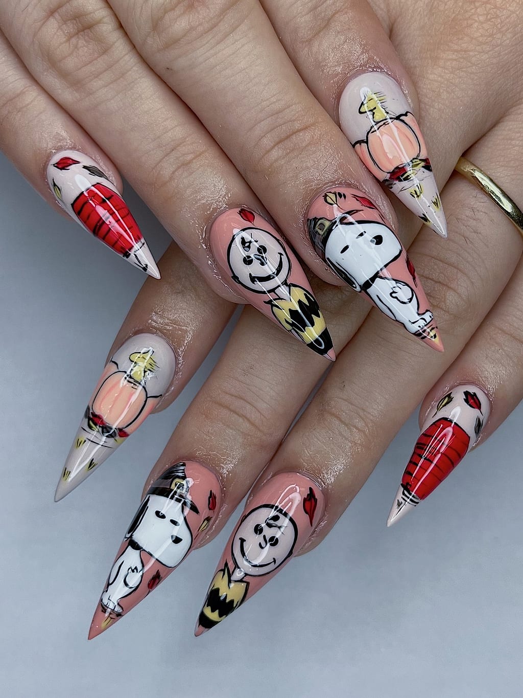 Nude stiletto nails featuring cartoon dog and cherry designs at Palace Nail Spa in Midtown Tallahassee