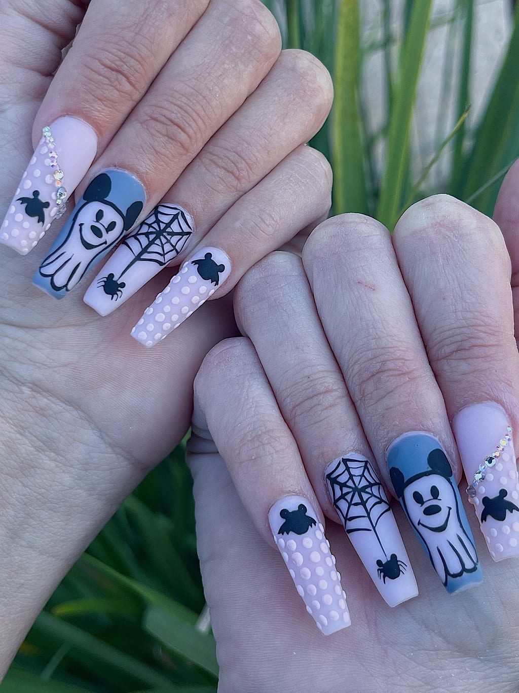 White coffin nails feature black spiderweb and skeleton Halloween art at Palace Nail Spa
