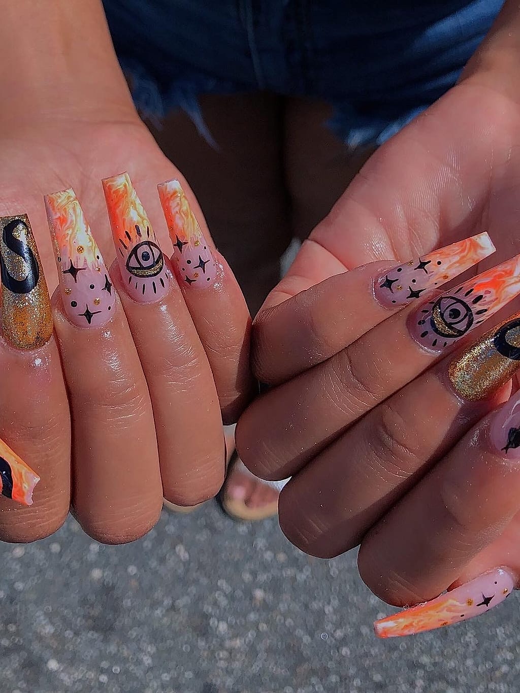 Nude nails with freehand orange line art, eye, and snake designs at Palace Nail Spa