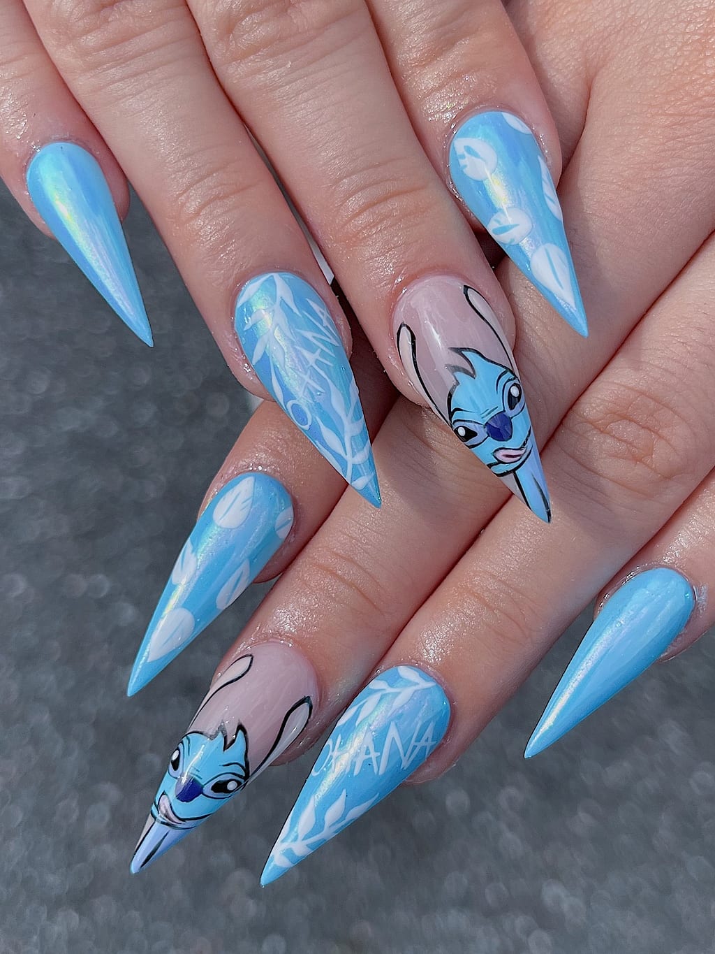 Sky blue stiletto nails with clouds and cartoon art at Palace Nail Spa in Midtown Tallahassee