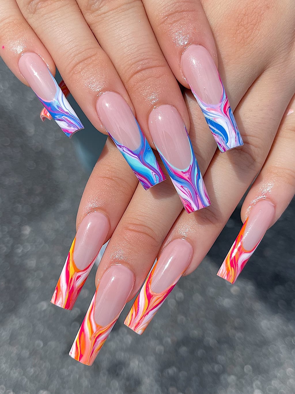 Nude French tips with orange and blue marbled flame art at Palace Nail Spa in Tallahassee
