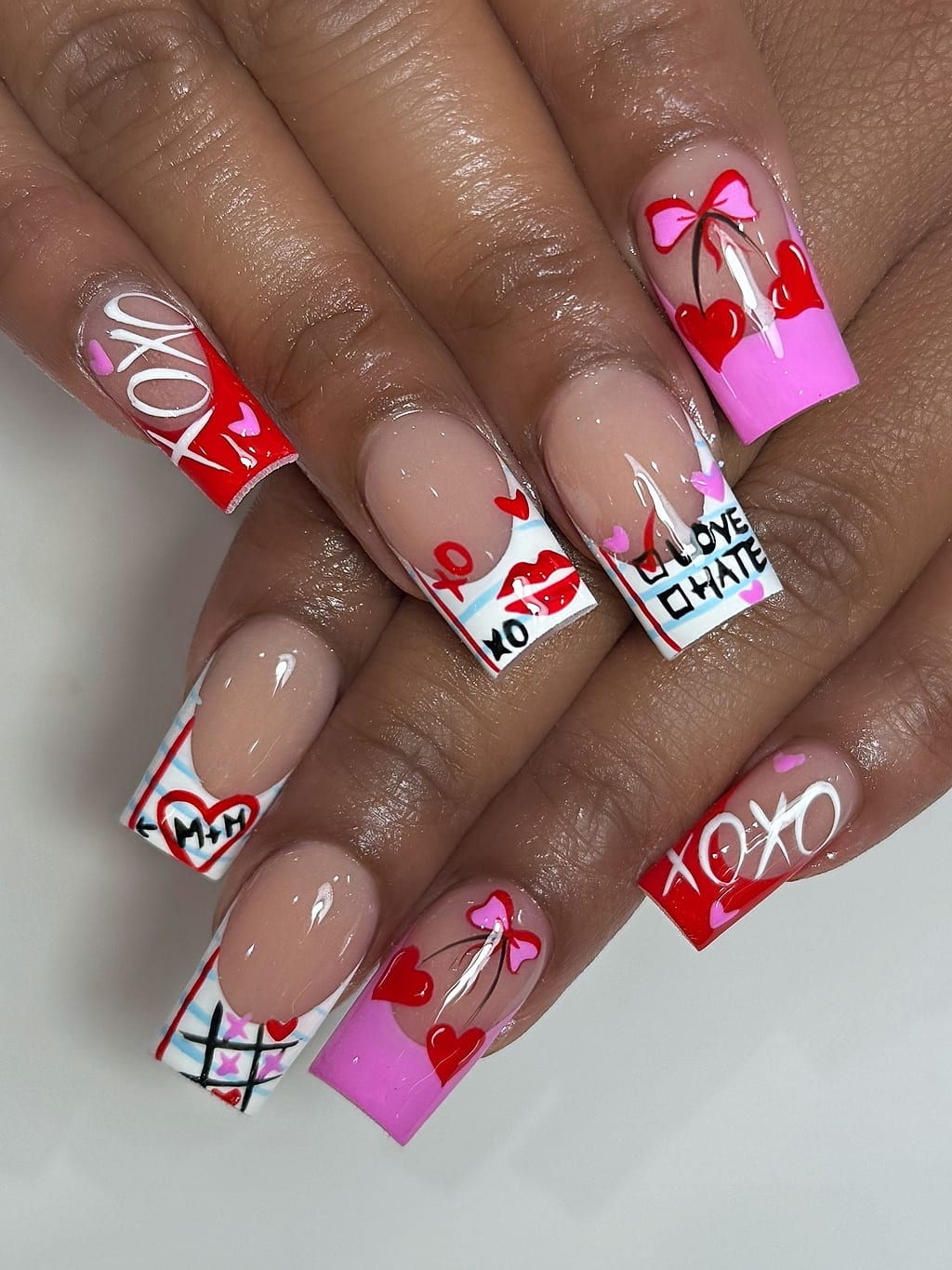Nude French tips with red hearts and Valentine lettering at Palace Nail Spa in Midtown Tallahassee