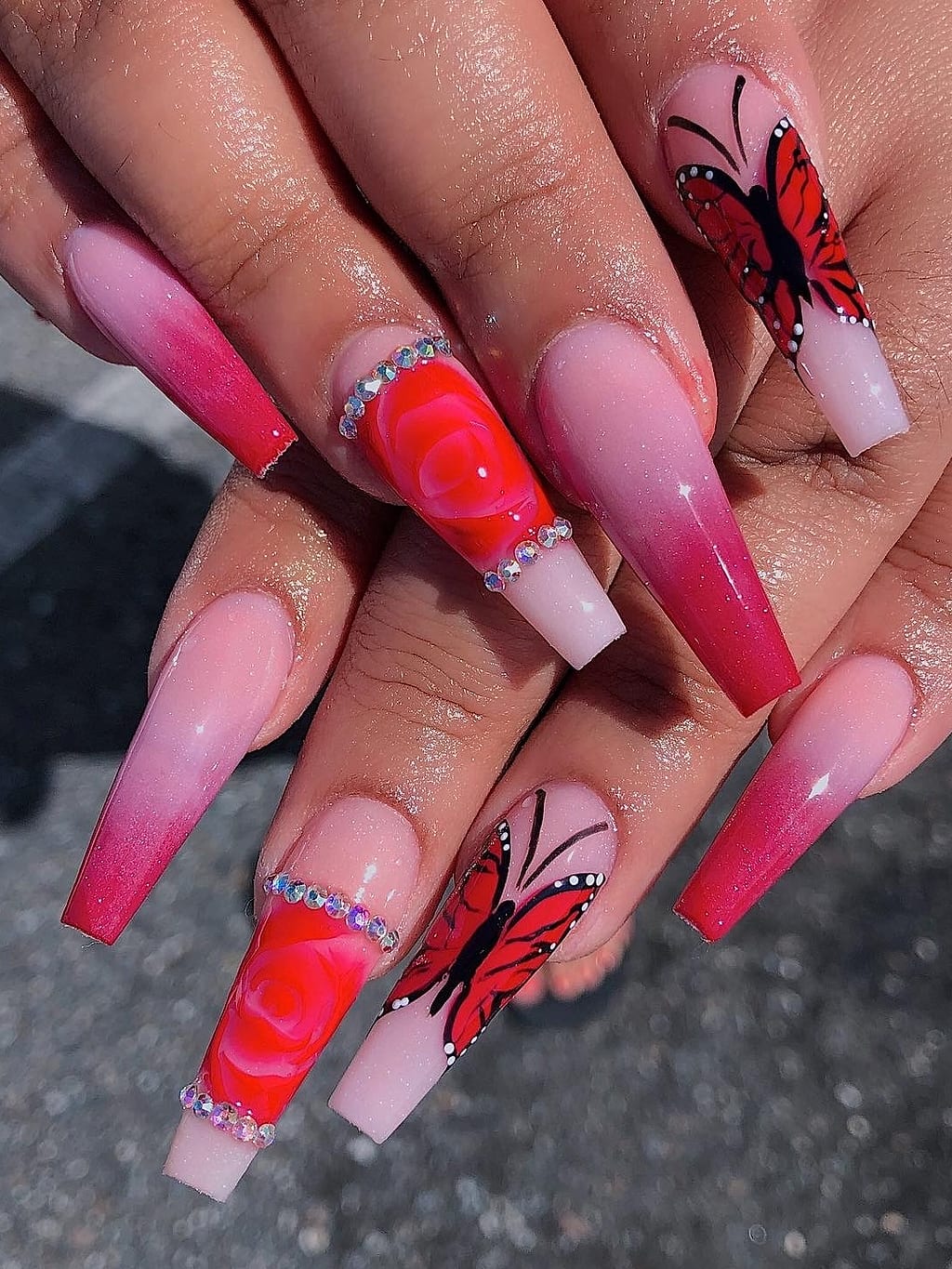 Pink ombre coffin nails with red butterfly art and rhinestone accents at Palace Nail Spa