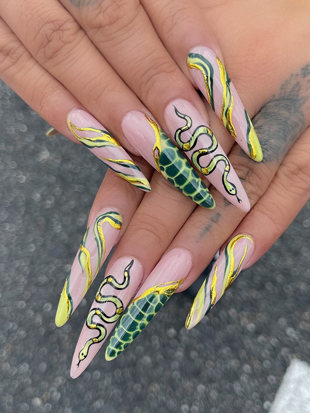 Nude stiletto nails with yellow and green snake designs at Palace Nail Spa in Midtown Tallahassee