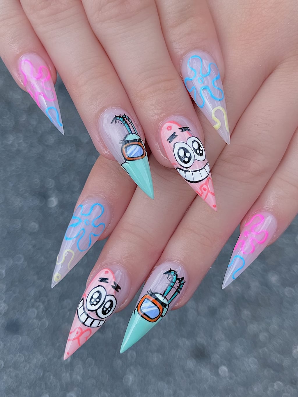 Pastel blue and pink stiletto nails with cartoon skull faces at Palace Nail Spa in Tallahassee