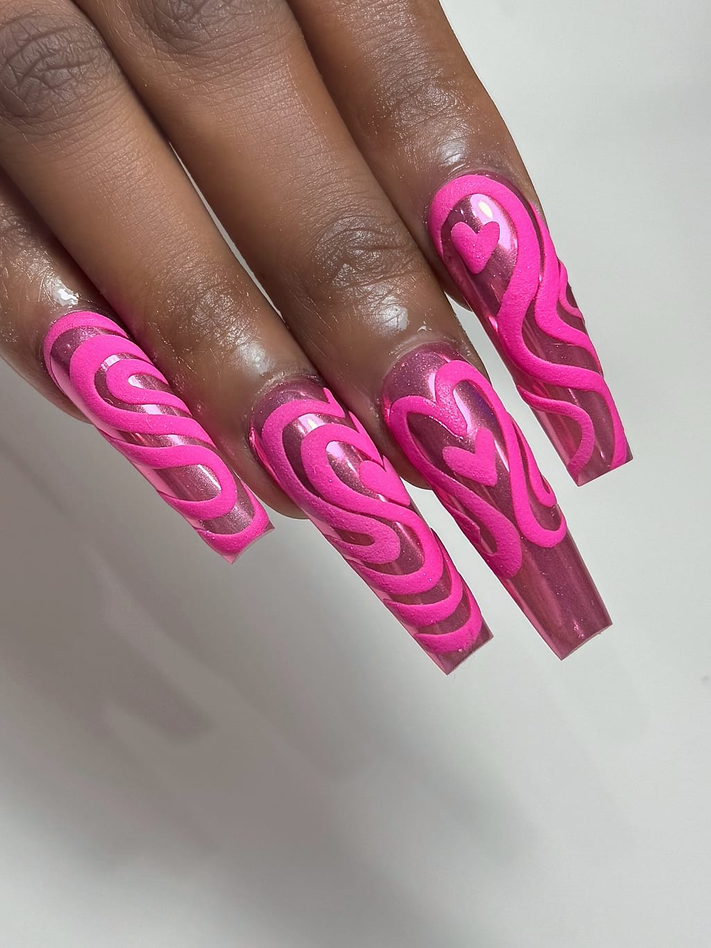 Long hot pink coffin nails with darker pink swirl art at Palace Nail Spa